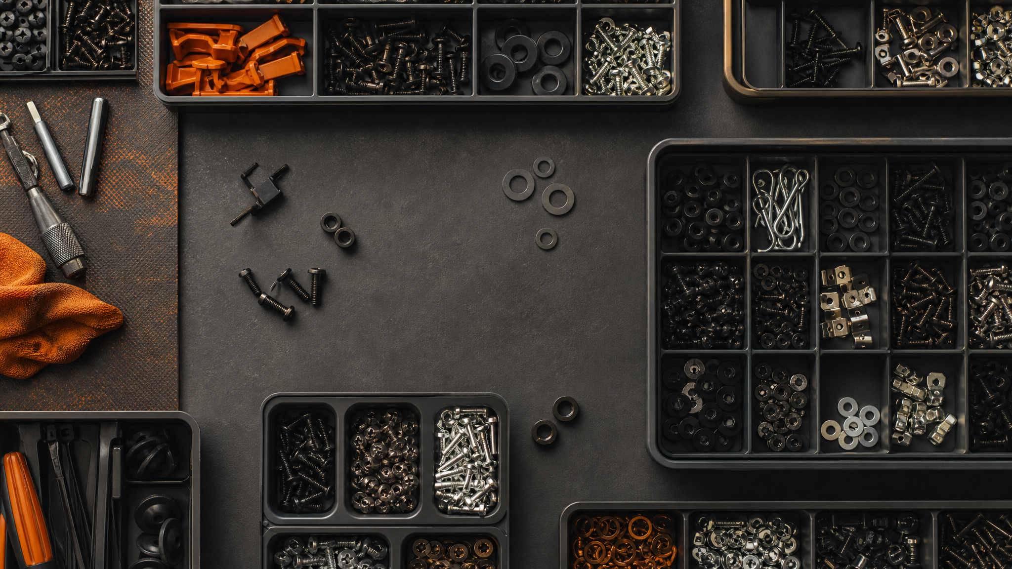 Overhead view of a tidy workbench covered with modular divided organiser trays full of sorted small hardware